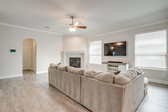 living room featuring crown molding, ceiling fan, a fireplace, vaulted ceiling, and light wood-type flooring