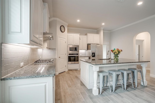 kitchen with a spacious island, a kitchen bar, light hardwood / wood-style flooring, stainless steel appliances, and white cabinets