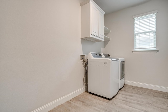 laundry room featuring cabinets, separate washer and dryer, and light hardwood / wood-style floors