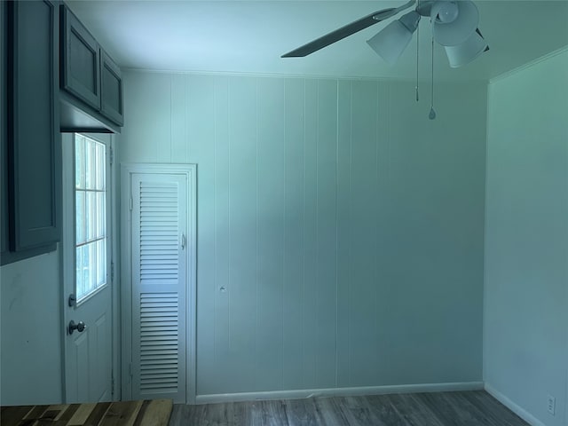 empty room featuring crown molding, wood walls, dark hardwood / wood-style flooring, and ceiling fan