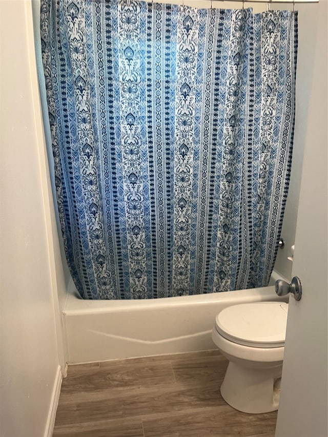 bathroom featuring wood-type flooring, toilet, and shower / bath combination with curtain