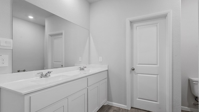 bathroom featuring toilet, double vanity, and hardwood / wood-style floors