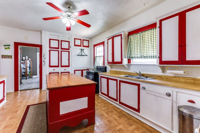 kitchen with black range with electric stovetop, ceiling fan, light parquet floors, sink, and a textured ceiling