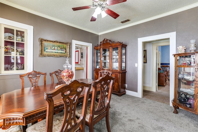 carpeted dining space featuring ceiling fan, ornamental molding, and a textured ceiling