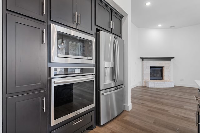 kitchen with appliances with stainless steel finishes, dark hardwood / wood-style floors, and a stone fireplace