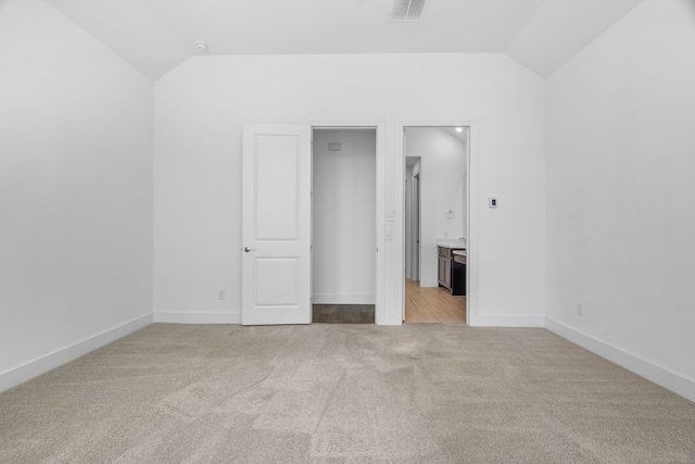 carpeted empty room with vaulted ceiling