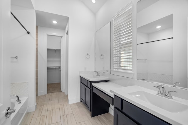 bathroom with a washtub, tile patterned floors, and vanity