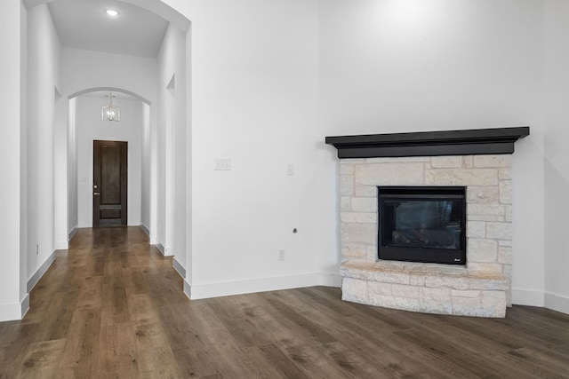 unfurnished living room with hardwood / wood-style floors and a stone fireplace