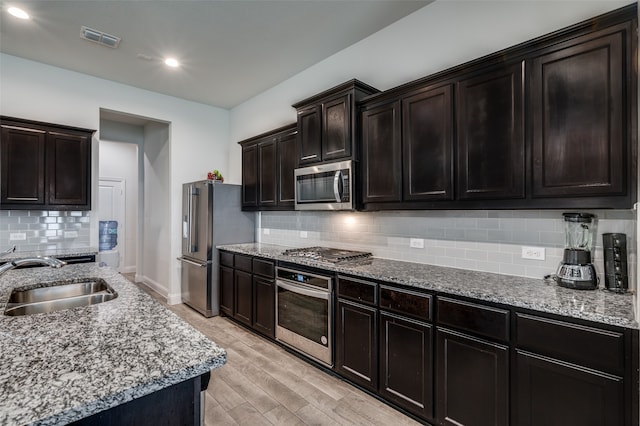 kitchen featuring light hardwood / wood-style flooring, sink, decorative backsplash, appliances with stainless steel finishes, and dark brown cabinetry