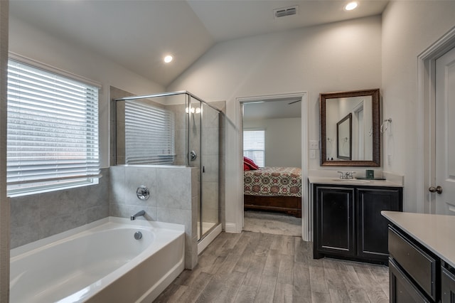 bathroom with vanity, a wealth of natural light, hardwood / wood-style flooring, and vaulted ceiling