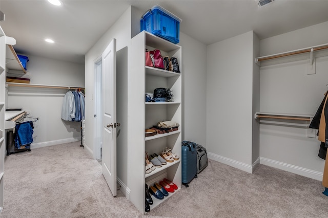 walk in closet with light colored carpet