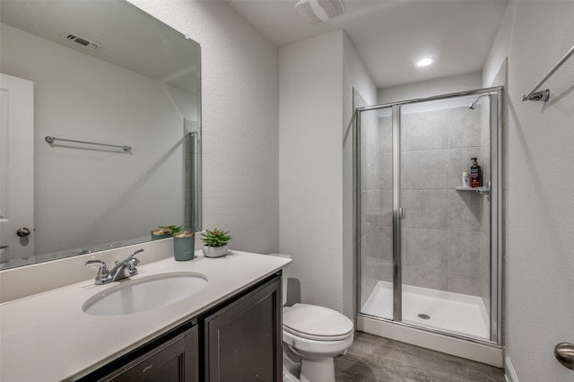 bathroom featuring vanity, toilet, wood-type flooring, and a shower with shower door