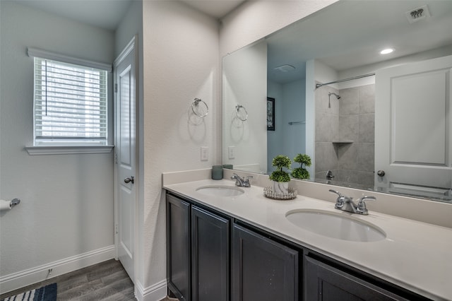 bathroom featuring wood-type flooring, a tile shower, and vanity