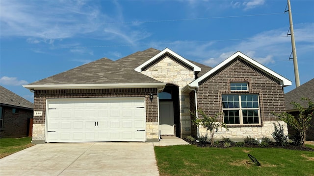 view of front facade with a garage, driveway, stone siding, roof with shingles, and a front yard