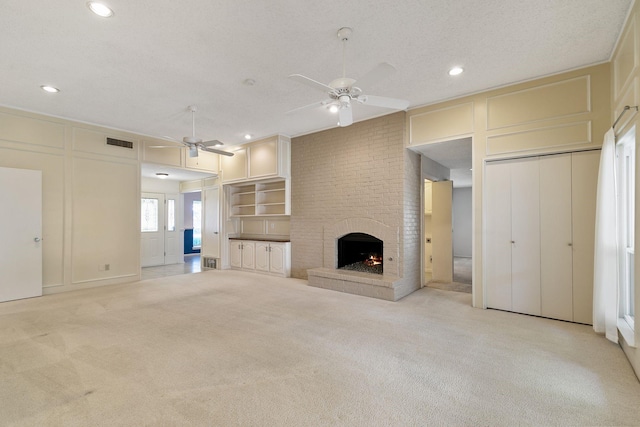 unfurnished living room with a fireplace, a textured ceiling, and light colored carpet