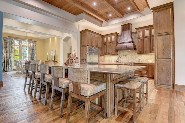 kitchen with wood ceiling, premium range hood, light wood-type flooring, and beam ceiling