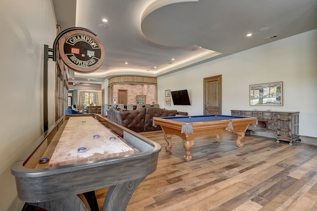 game room featuring light wood-type flooring, a raised ceiling, and billiards