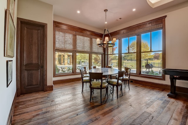 dining room with an inviting chandelier, a healthy amount of sunlight, and wood-type flooring