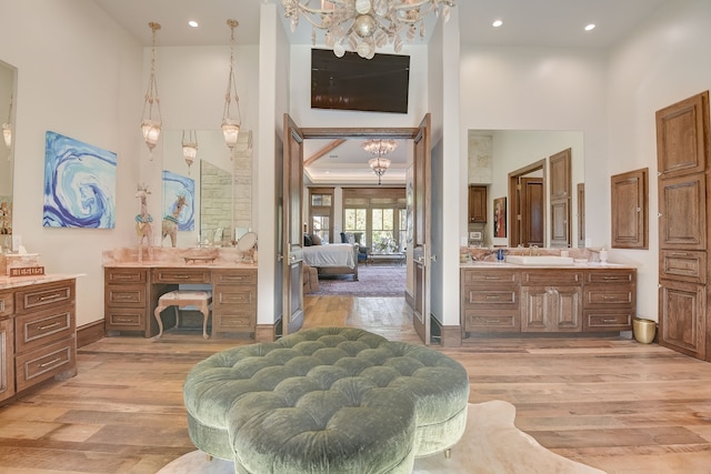 bathroom featuring an inviting chandelier, vanity, a high ceiling, and wood-type flooring