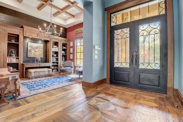 foyer entrance with coffered ceiling, french doors, parquet flooring, a notable chandelier, and beamed ceiling