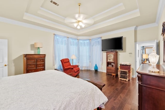 bedroom featuring ornamental molding, dark hardwood / wood-style flooring, ceiling fan, and a tray ceiling