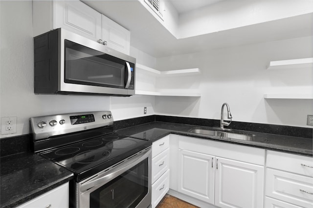 kitchen featuring appliances with stainless steel finishes, white cabinets, dark stone counters, and sink