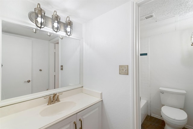 full bathroom featuring toilet, a textured ceiling, tiled shower / bath combo, and vanity