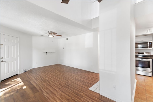 unfurnished living room featuring ceiling fan, a textured ceiling, and light hardwood / wood-style floors