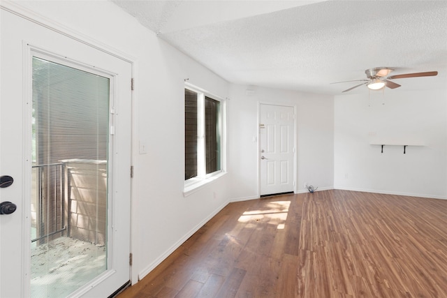 unfurnished room with a textured ceiling, dark wood-type flooring, and ceiling fan