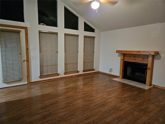 unfurnished living room with a tiled fireplace, ceiling fan, high vaulted ceiling, and wood-type flooring