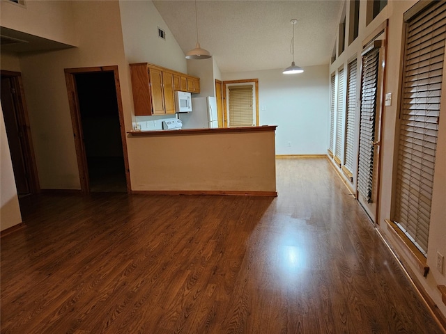 kitchen featuring white appliances, hanging light fixtures, kitchen peninsula, and dark wood-type flooring