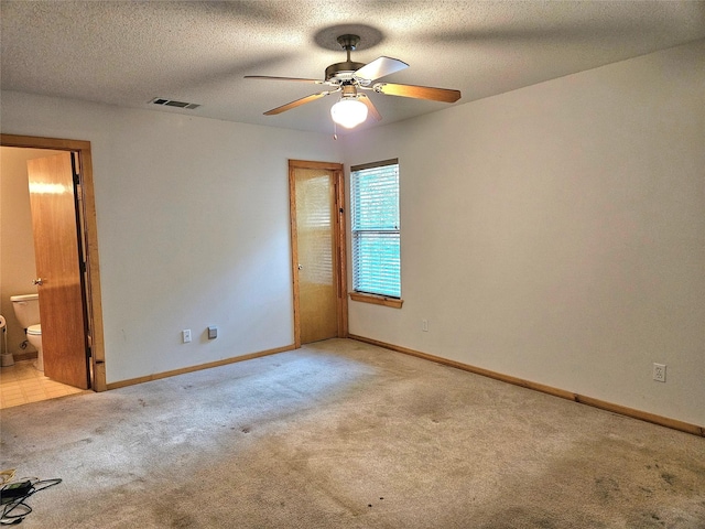 unfurnished room featuring ceiling fan, light colored carpet, and a textured ceiling