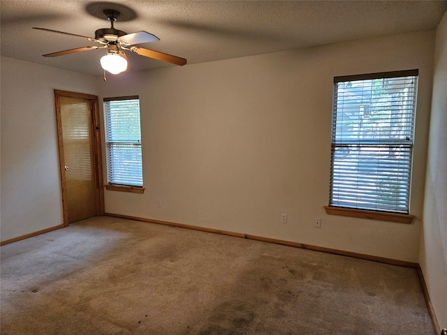 empty room featuring light colored carpet, ceiling fan, and plenty of natural light