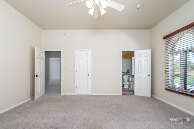 unfurnished bedroom featuring light colored carpet, ensuite bathroom, and ceiling fan