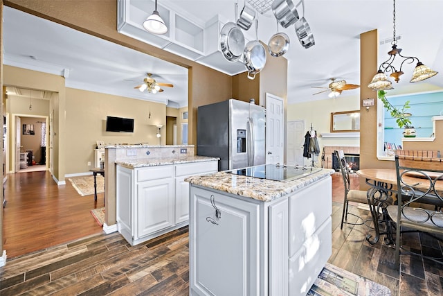 kitchen with pendant lighting, stainless steel fridge, open floor plan, and white cabinets