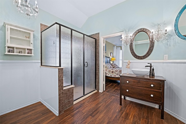 ensuite bathroom featuring connected bathroom, a chandelier, a sink, and wood finished floors