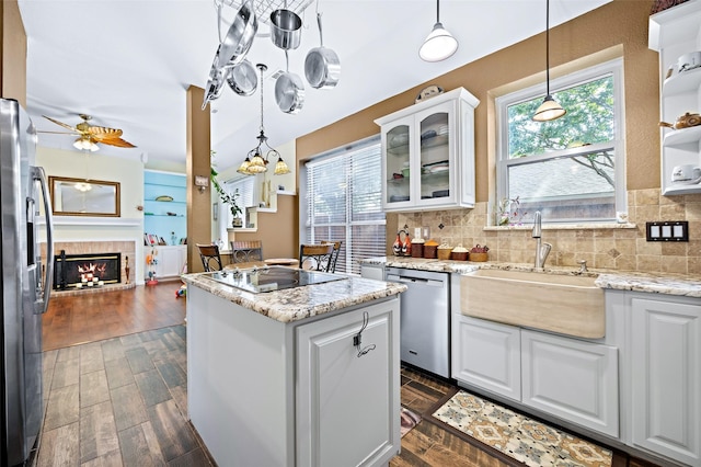 kitchen featuring stainless steel appliances, a fireplace, white cabinetry, light stone countertops, and glass insert cabinets