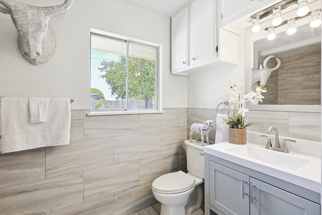 bathroom with tile walls, toilet, and vanity