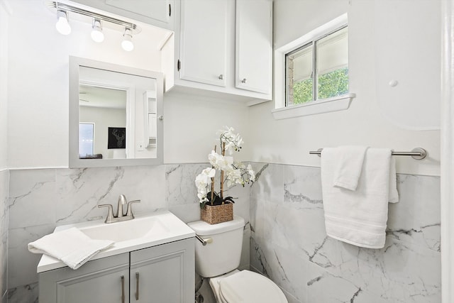 bathroom featuring tile walls, toilet, rail lighting, and vanity