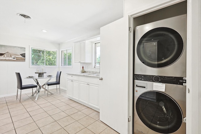 laundry room featuring light tile patterned floors, sink, and stacked washer and dryer