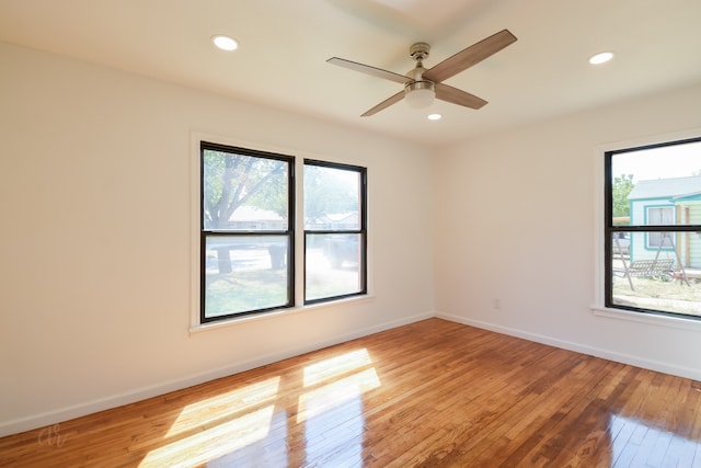 spare room featuring a wealth of natural light, hardwood / wood-style floors, and ceiling fan