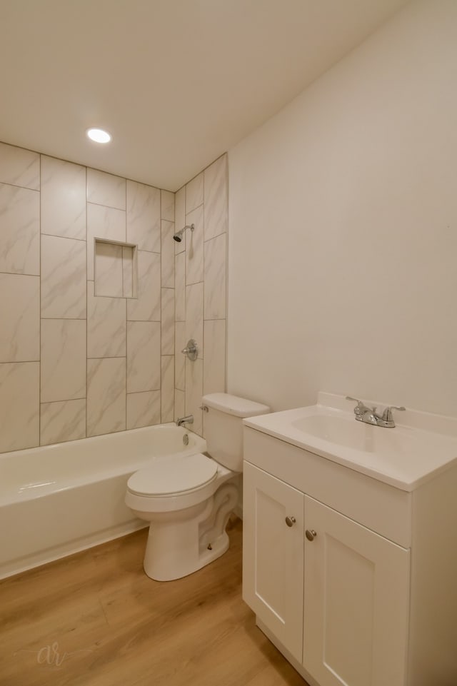 full bathroom featuring hardwood / wood-style flooring, tiled shower / bath, toilet, and vanity