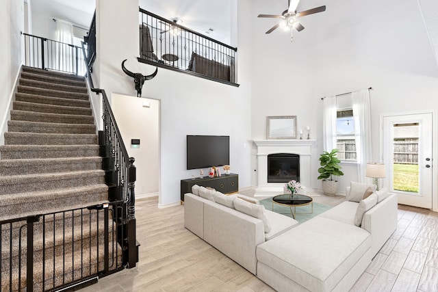 living room with stairs, a glass covered fireplace, light wood-style flooring, and baseboards