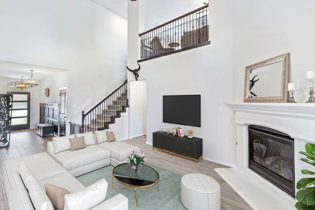 living room featuring a high ceiling, a notable chandelier, and wood-type flooring