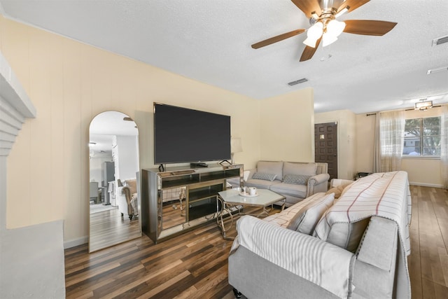 living room with dark hardwood / wood-style flooring, a textured ceiling, and ceiling fan