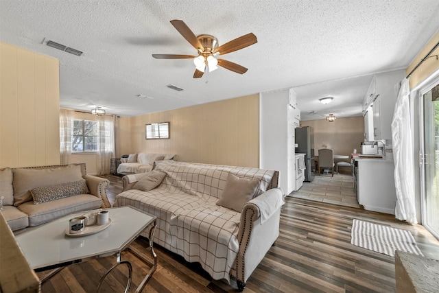 living room featuring ceiling fan, hardwood / wood-style flooring, a textured ceiling, and a healthy amount of sunlight