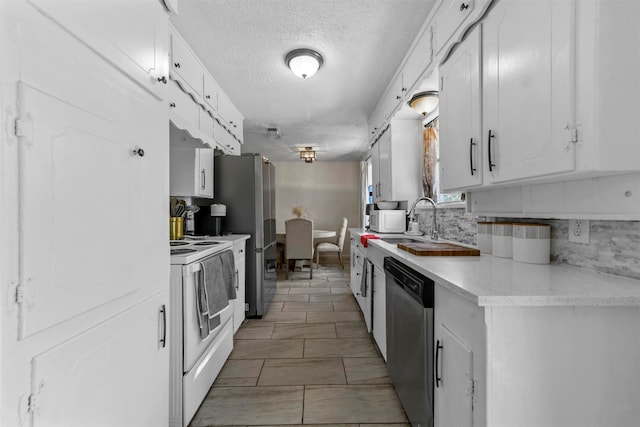 kitchen with sink, appliances with stainless steel finishes, a textured ceiling, tile patterned flooring, and white cabinets