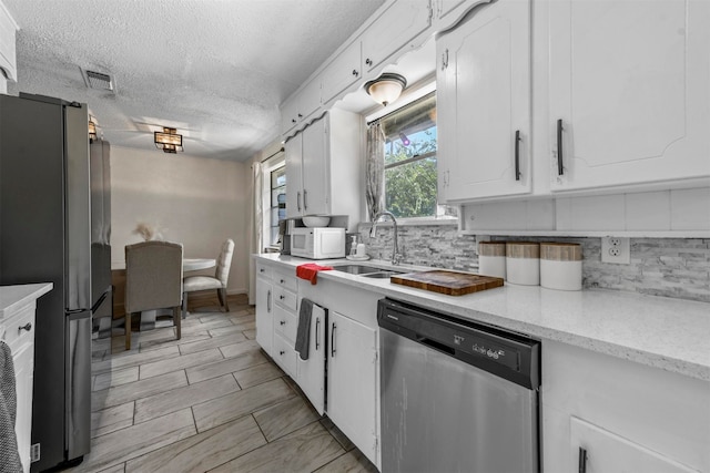 kitchen featuring appliances with stainless steel finishes, decorative backsplash, light stone counters, white cabinets, and light tile patterned floors