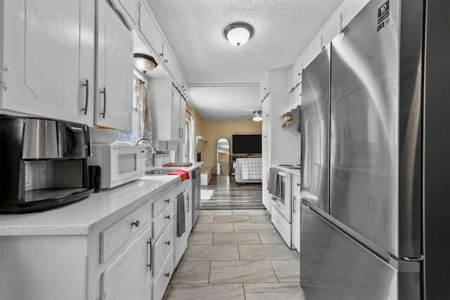 kitchen with ceiling fan, white cabinetry, appliances with stainless steel finishes, and light hardwood / wood-style floors