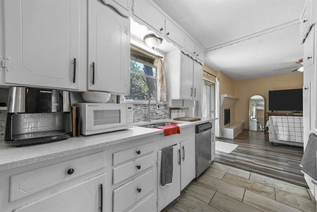 kitchen featuring ceiling fan, dishwasher, light hardwood / wood-style floors, and tasteful backsplash